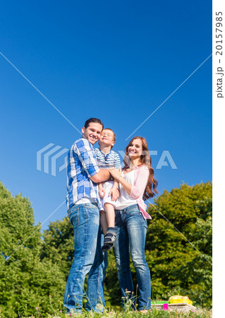 Family carrying kid, the parents standing on meadow 20157985