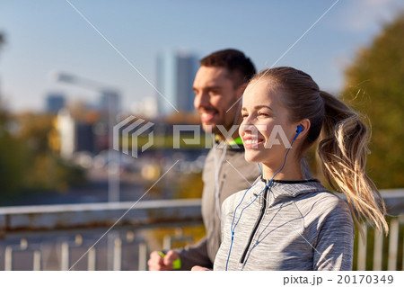 happy couple with earphones running in city 20170349