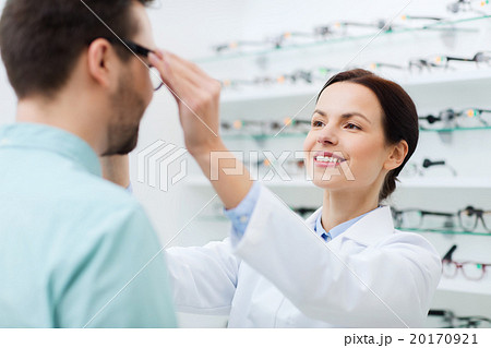 optician putting on glasses to man at optics store 20170921