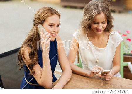 happy young women with smartphones at outdoor cafe 20171766
