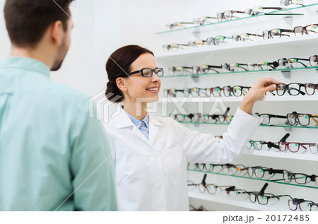 optician showing glasses to man at optics store 20172485