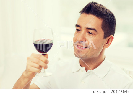 happy man drinking red wine from glass at home 20172645