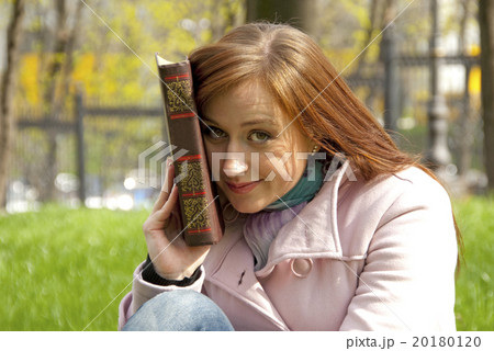 Beautiful redhead woman reading book on a meadow Beautiful redhead woman reading book on a meadow 20180120