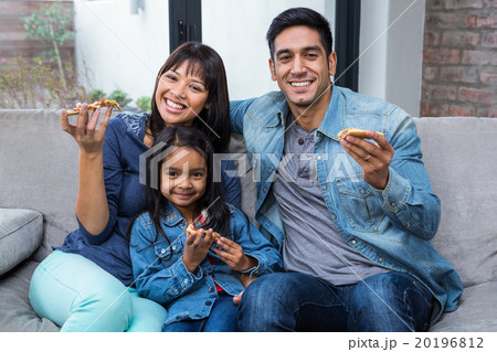 Smiling family eating pizza on the sofa Smiling family eating pizza on the sofa 20196812