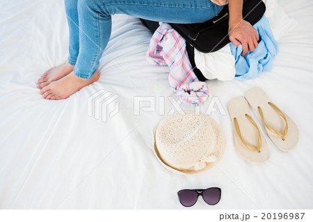 Woman sitting on her overfull suitcase Woman sitting on her overfull suitcase 20196987