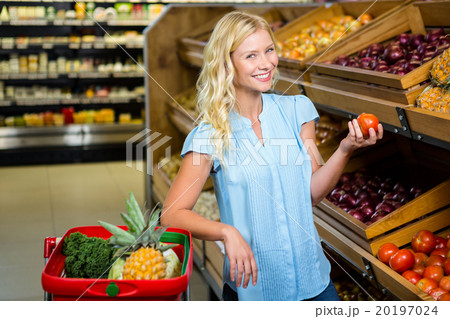 Smiling blonde woman holding tomato 20197024