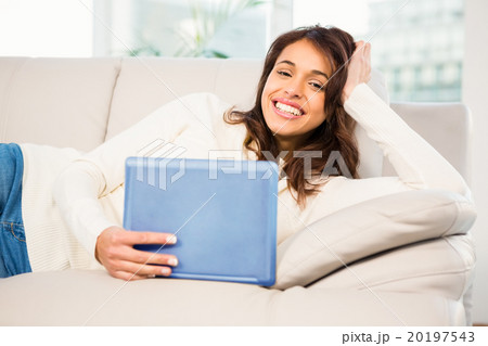 Smiling woman using her tablet on couch 20197543