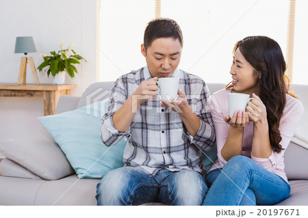 Happy woman looking at man while holding coffee cup 20197671