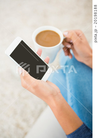 Close up view of a woman holding coffee and smartphone Close up view of a woman holding coffee and smartphone 20198188