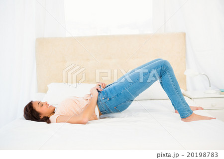 Casual smiling woman trying to close her jeans 20198783