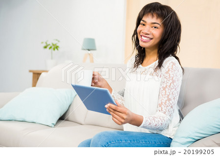 Casual smiling woman using tablet on the couch 20199205