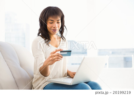 Smiling casual woman buying things with her laptop 20199219