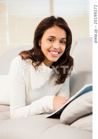 Pretty brunette reading magazine on the couch Pretty brunette reading magazine on the couch 20199272