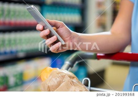 Woman with cart using smartphone  20199368