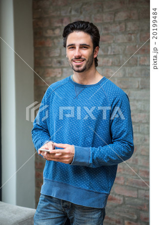 Handsome man using smartphone in living room 20199484