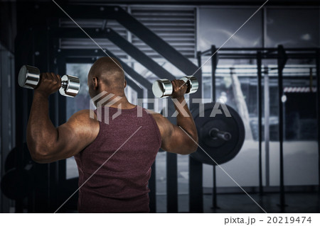 Composite image of fit man exercising with dumbbell  20219474
