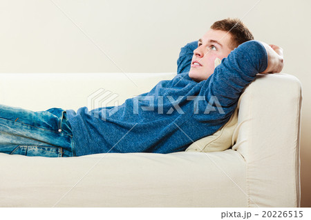 Young pensive man relaxing on couch 20226515