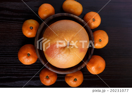 Grapefruit in wooden plate with mandarines on dark 20231077