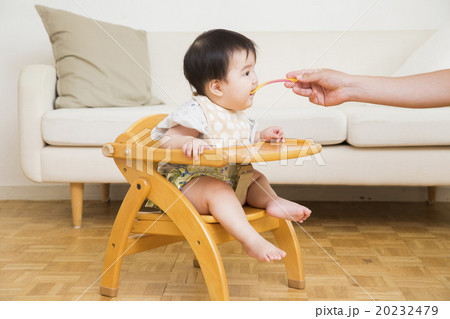 べビーチェアに座って離乳食を食べる赤ちゃん 20232479