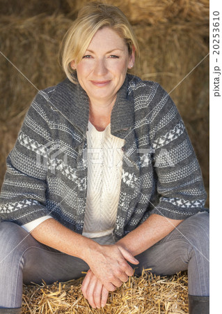 Middle Aged Blond Woman Sitting on Hay Bale 20253610