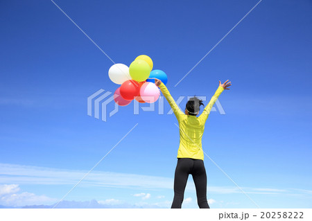 young cheering woman with colorful balloons on mountain peak 20258222