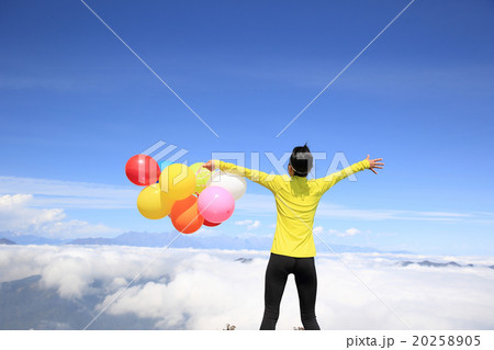 young cheering woman with colorful balloons on mountain peak young cheering woman with colorful balloons on mountain peak 20258905