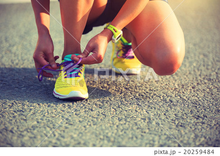 young woman runner tying shoelaces on city road young woman runner tying shoelaces on city road 20259484