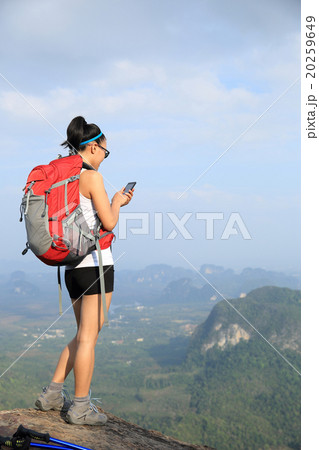 young woman hiker use cellphone on mountain peak 20259649