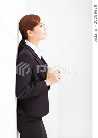relaxed businesswoman leaning against white wall in office relaxed businesswoman leaning against white wall in office 20299829