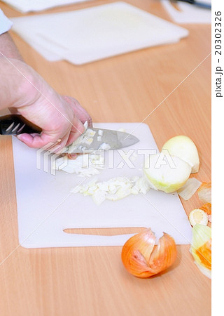 Chef chopping onion with a knife on cutting board 20302326