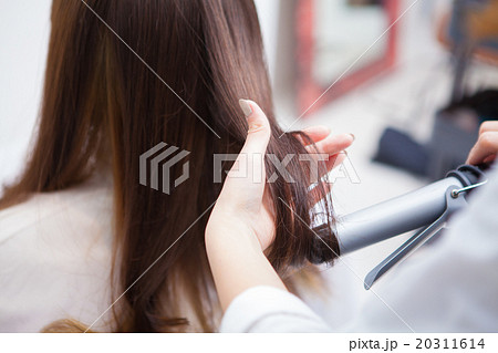 ヘアアイロンをあてる女性美容師 20311614
