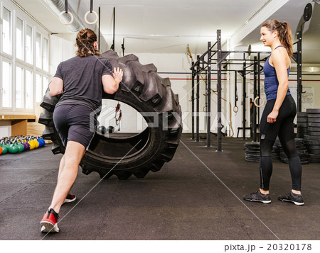 Couple working out with tire at crossfit gym 20320178