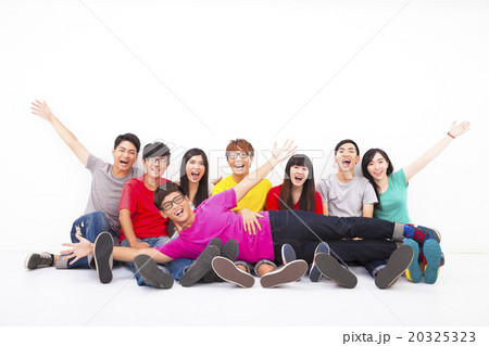 Happy young group sitting together against white wall 20325323