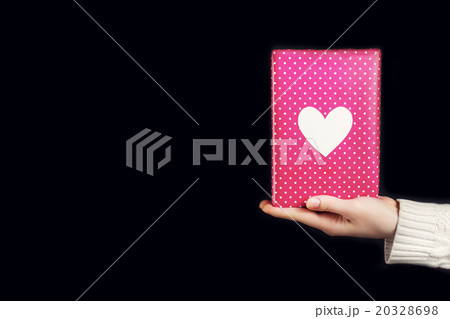 Hand holding pink gift isolated on black 20328698