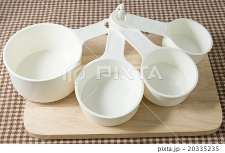Four Plastic Measuring Cups on Wooden Board Four Plastic Measuring Cups on Wooden Board 20335235