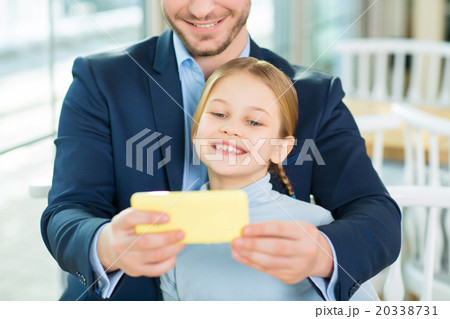 Young adoring dad taking picture of cute daughter. 20338731