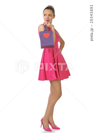 Pretty blond woman in pink dress holding gift bag Pretty blond woman in pink dress holding gift bag 20343891