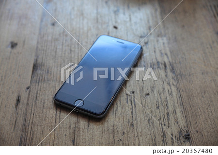 オシャレな木目のテーブルの上に置かれたスマートフォン スマホ の画像 写真 の写真素材