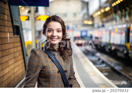 Young woman in brown winter coat waiting on trainの写真素材