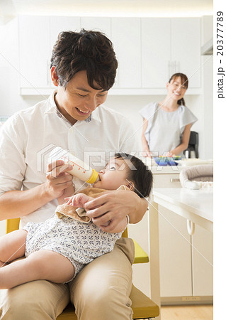赤ちゃんにミルクを飲ませる若いお父さん 赤ちゃんにミルクを飲ませる若いお父さん 20377789