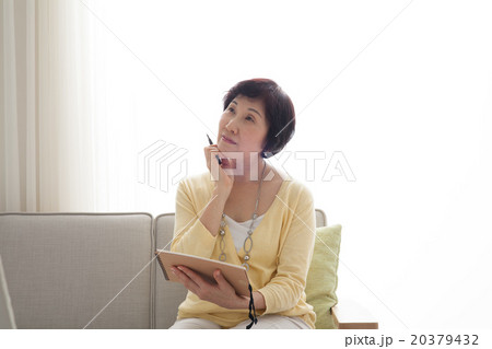 ミドル女性　ソファでノートを書く　考え事 20379432