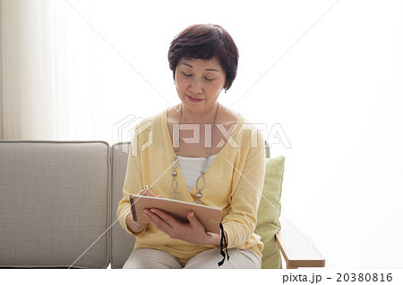 ミドル女性　ノートに書く　ソファ　座る 20380816