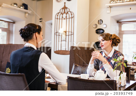 Two pretty girl-friends talk in cafe Two pretty girl-friends talk in cafe 20393749