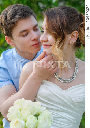 groom kisses the bride on a background of green leaves in the sp groom kisses the bride on a background of green leaves in the sp 20429029
