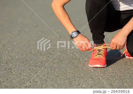 sports woman runner tying shoelace on city road 20439918