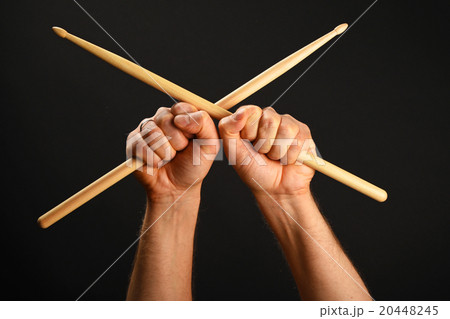 Two hands with crossed drumsticks over black Two hands with crossed drumsticks over black 20448245