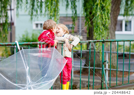 Two little kid boys with big umbrella outdoors Two little kid boys with big umbrella outdoors 20448642