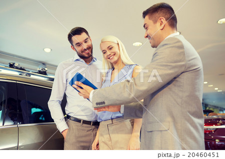 happy couple with car dealer in auto show or salon 20460451