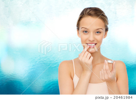 smiling young woman applying lip balm to her lips smiling young woman applying lip balm to her lips 20461984