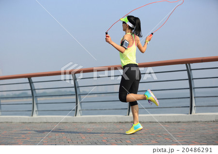young fitness woman jumping rope at seaside 20486291